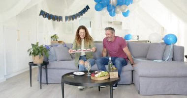 Doğum günü pankartı son sınıf çifti mum ışığında tatlı tepsisi taşıyor, şarap dolduruyor, kadeh kaldırıyor. Romantik, kutlama, samimiyet, şen, samimi, neşeli, zarif