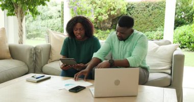 Finansal konular, dizüstü bilgisayar kullanan ve belgeleri evde tutan Afro-Amerikan bir çift. technology, bütçe, planlama, evrak işleri, yaşam tarzı, takım çalışması