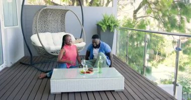 Afro-Amerikan çiftlerin balkona yerleşip içki içip kadeh kaldırmalarına rehberlik eden hamur işleri. Romantizm, boş zaman, açık hava, rahatlama, samimiyet, yaşam tarzı, doğal