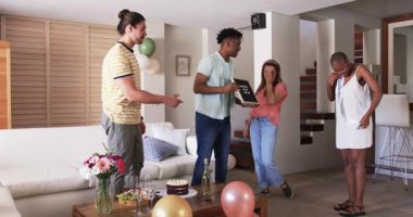 Arkadaşlar evde pasta ve balonlarla kutlama yapıyor, birlikte neşeli anlar paylaşıyorlar. Kutlama, arkadaşlık, parti, mutluluk, toplanma, birliktelik