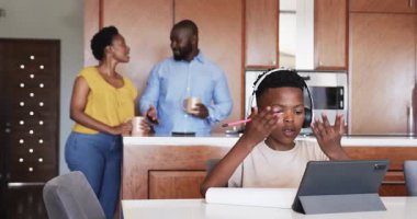 Ebeveynler Homd 'da kahvenin tadını çıkarırken, küçük çocuk tablet ve kulaklıkla ders çalışıyor. Çocuk, öğrenme, teknoloji, aile, bağlanma, ebeveynlik