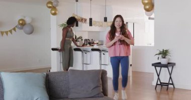 Afro-Amerikalı, Asyalı arkadaşlar modern mutfakta doğum gününü pankartlar ve balonlarla kutluyorlar. Kutlama, dostluk, toplantı, mutfak, dekor, neşe, parti, nişan