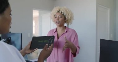 Modern ofis ortamında tablet projesini tartışan iki kadın. İş, teknoloji, işbirliği, takım çalışması, beyin fırtınası, dijital