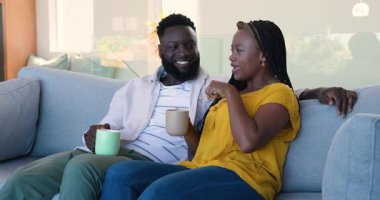 Afrika kökenli Amerikalı bir çift oturma odasındaki kanepede oturmuş el kol hareketi yapıyor, fincanları kızartıyorlar. Romantik, samimi, canlı, konuşkan, samimi, modern, sevecen.