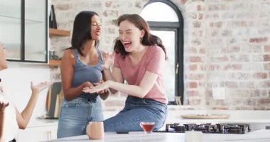 Mutfak adasında çay yudumlayan yakın arkadaşlar nişan yüzüğünü fark edip evlenme teklifini kutluyorlar. Arkadaşlık, kutlama, yakınlık, evcil, sıcak, samimi, neşeli