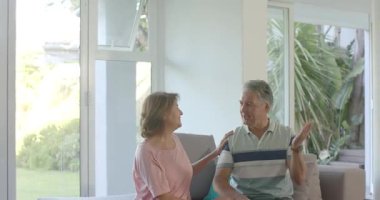 Afrikalı Amerikalı bakıcı konuşmak için tekerlekli sandalyeye oturan yaşlı çifti sandalyeye oturtuyor. Şefkat, bağlantı, destek, aile, dinginlik, bakım, aile içi