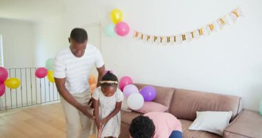 Afrikalı Amerikalı bir aile pastel balonlarla ve konfeti atarak doğum günü partisini kutluyor. Doğum günü, kutlama, renkli, neşeli, aile, neşe, neşe