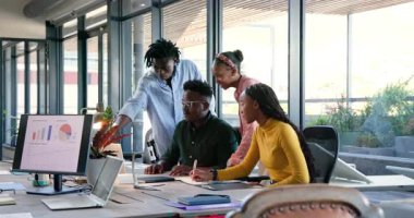 Afro-Amerikalı iş arkadaşları ofisteki çizelgelere cevap veriyor, bulguları daktilo edip alkışlıyorlar. İşbirliği, takım çalışması, veri analizi, ofis ortamı, modern çalışma alanı, profesyonel büyüme, iş başarısı