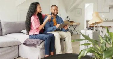 Oturma odasına giren Afro-Amerikan çift tableti açıyor, eşyaları tıkırdatıyor, kart detaylarını giriyorlar. Teknoloji, yaşam tarzı, modern, samimiyet, işbirliği, rahatlık, rahatlık