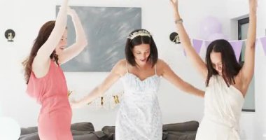 Üç bayan arkadaş, taç arkadaşının evde konfeti kepçelerken gülümsemesinden sonra doğum gününü kutluyor. Şenlik, dostluk, neşe, kutlama, yaşam tarzı, hayat dolu, neşeli