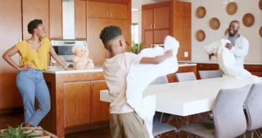 Mutfakta, aile yastık savaşı yapıyor, birlikte neşeli anlar paylaşıyorlar, evde. Bağlanma, birliktelik, mutluluk, eğlence, ev hayatı, kahkaha