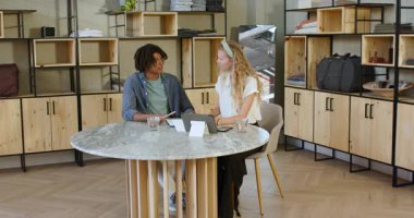 Çeşitli iş arkadaşları kapalı ofis alanında, tabletli mermer masanın yanında yürüyor ve kutluyor. Kutlama, meslektaşlar, takım çalışması, işbirliği, modern, ofis, tartışma