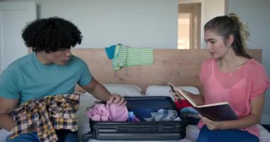 Genç çift yataklarına bavullarını topluyor, birlikte seyahat macerasına hazırlanıyorlar, evde. tatil, bagaj, keşif, yolculuk, hazırlık