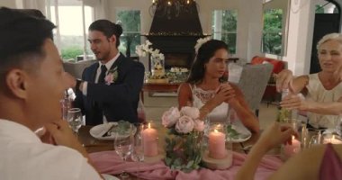 Damat tost üstüne kadeh kaldırıyor, ahşap masada konuklar için şampanya dolduruyor. Kutlama, zarafet, yoldaşlık, sofistike, sıcaklık, mutluluk, samimiyet.