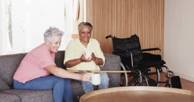 Üst düzey bayan arkadaşlar evde iyileşme kutlamaları yapıyorlar, baston ve tekerlekli sandalye kullanıyorlar. İyileşme, dostluk, destek, birliktelik, neşe, sağlık, kutlama