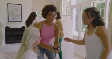 Evde bir sürü kadın telefonun etrafında toplanıp elbise fotoğraflarını karıştırıyor. Aile, arkadaşlık, bağlantı, gündelik, modern, sıcak, iletişim