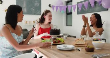 Pasta yerleştirmeye ve doğum günü pastasını kesmeye tepki veren çeşitli bayan arkadaşlar. Kutlama, dostluk, neşe, zarafet, yaşam tarzı, iç mekan, sıcaklık