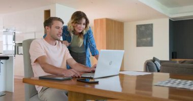 Evde dizüstü bilgisayarda işbirliği yapan bir çift modern mutfakta proje tartışıyorlar. İşbirliği, takım çalışması, teknoloji, yaşam tarzı, ortaklık, iletişim