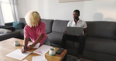 Bir kadın, evinde, kanepede dizüstü bilgisayar kullanarak projeyi tartışıyor. İşbirliği, takım çalışması, beyin fırtınası, teknoloji, arkadaşlık, iletişim