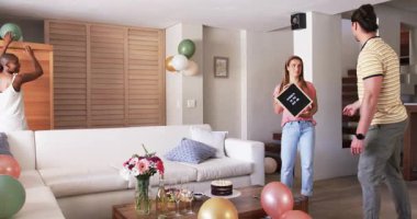 Partide, arkadaşlar doğum gününü evde kutluyor, süslemeleri ve pastayı heyecanla düzenliyor. Kutlama, parti, mutluluk, arkadaşlık, etkinlik, toplantı