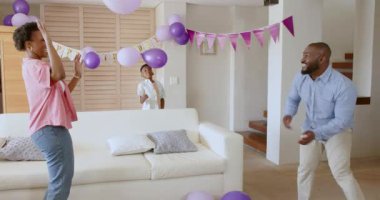 Aile evde doğum gününü balonlarla kutluyor, gülümsüyor ve birlikte oynuyorlar. Kutlama, birliktelik, mutluluk, neşe, toplanma