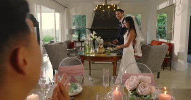 Asyalı gelin ve damat pasta masasına geri adım attıktan sonra katmanlı düğün pastası kesiyorlar. Kutlama, romantizm, zarafet, mutluluk, gelenek, dekor, festival