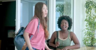 Afro-Amerikalı, Asyalı arkadaşlar tatilde kapalı bir yere, ahşap masaya telefon ve çantayla geliyorlar. Tatil, arkadaşlık, seyahat, macera, birleşme, manzara, rahatlama