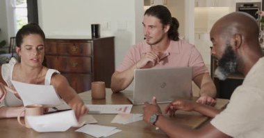 Yemek masasındaki çizelgeleri sıralamak, çeşitli iş arkadaşları gümüş dizüstü bilgisayarlarla kağıtları gözden geçirip işbirliği yapmak. İşbirliği, takım çalışması, tartışma, ofis, strateji, beyin fırtınası, iletişim