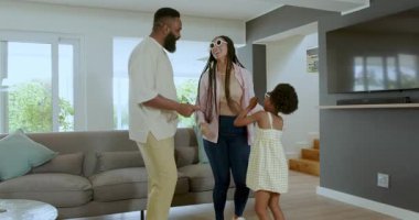 Çeşitli aileler, kızlarının modern oturma odasında, kanepelerinde güneş gözlükleriyle okula hazırlanmasına yardım ediyor. Aile, ebeveynlik, eğlence, modern, iç mekan, sıcaklık, rutin, işbirliği