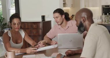 Çeşitli iş arkadaşları evde iş birliği yapıyor. Dizüstü bilgisayardan üst düzey organizasyon kağıtları olarak geçen bir kadın. İşbirliği, takım çalışması, beyin fırtınası, iletişim, yaratıcılık, profesyonel, çok yönlü