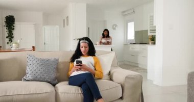 Anne, genç kız olarak kanepeye zarf getiriyor telefonu kaydırıyor, mektup okuyor, haberleri paylaşıyor. Aile, iletişim, bağlantı, sevgi, modern, yaşam tarzı, iç mekan