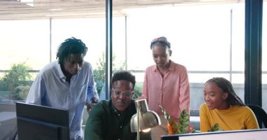 Afro-Amerikalı iş arkadaşları ofis masasındaki tezahürat başarısını izleyip analiz ediyorlar. İşbirliği, takım çalışması, ofis, veri, analitik, modern, profesyonel