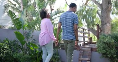 Genç bir adam bahçede, yemyeşil çimlerle çevrili bir kadına sürpriz yapmayı teklif ediyor. Romantizm, nişan, evlilik teklifi, aşk, bahçede, doğada