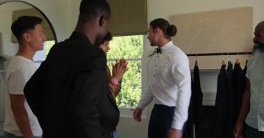 Çeşitli erkek takımları oturma odasında toplanıp müşterilerini ölçüyor ve donanma ceketini uygun hale getiriyor. Terzilik, moda, zarafet, zanaat, danışmanlık, tarz, meslek