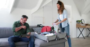 Üst düzey çift tişört teslim, tablet tıkırtısı, tavan arası gezisi için bavul hazırlama. Çift, paketleme, seyahat, organizasyon, yaşam tarzı, modern, yerli