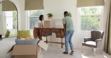 Çeşitli kutular taşıyan, ahşap masa çeviren ve yatak odalarını döşeyen çift. İşbirliği, ev dekorasyonu, iç tasarım, yaşam alanı, sıcaklık, takım çalışması, günlük tarz