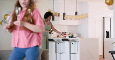 Afrikalı Amerikalı ve Asyalı arkadaşlar modern kapalı mutfak çantalarını hazırlıyorlar, doğum günü hediyelerini düzenliyorlar. Arkadaşlar, kutlama, paketleme, modern, dekor, neşeli, takım çalışması, organizasyon