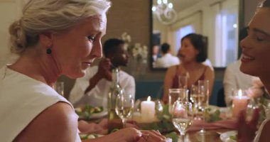 Şölen masasında kadeh kaldırdıktan sonra büyük anne ve Asyalı kız el ele tutuşup yüzüğe sarılıyorlar. Nesiller, kutlamalar, yakınlık, zarafet, gelenek, duygusal, aile