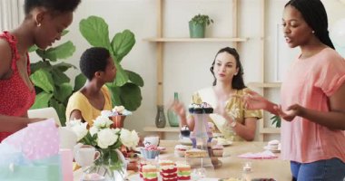 Çeşitli bayan arkadaşlar hediyeleri ayarlıyor, kart okuyor ve gelin partisinde ikramda bulunuyorlar. Kutlama, dostluk, zarafet, pastel, neşe, olay, dekor
