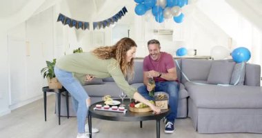 Son sınıf çifti doğum gününü evde kutluyor keklerin üzerine mum koyuyor ve şampanya döküyor. Romantik, samimi, neşeli, zarif, samimi, dekoratif.