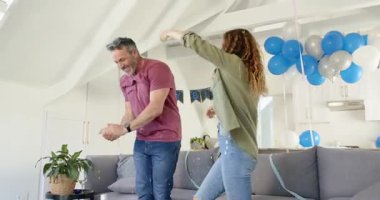 Çatı katında doğum gününü kutlayan bir çift, konfeti üfleyen bir adam, kadını aperatiflerin yanında döndüren bir kadın. Şenlikler, kutlamalar, neşe, eğlence, yaşam tarzı, modern, gündelik