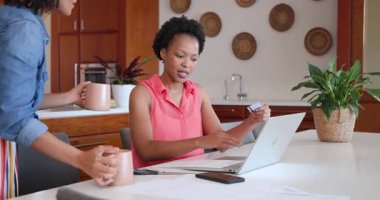 Evde dizüstü bilgisayarda işbirliği yapan, gülümseyen ve fikirleri tartışan çeşitli kadın çiftler. İşbirliği, takım çalışması, iş, uzaktan çalışma, beyin fırtınası, teknoloji