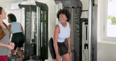 Afrikalı Amerikalı ve Asyalı arkadaşlar spor salonunda çalışıyor ellerinde bant tutuyor ve ağırlık kaldırıyorlar. Fitness, motivasyon, sağlık, takım çalışması, egzersiz, kararlılık, sağlık