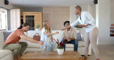 Arkadaşları evde gündelik sohbetten hoşlanıyor, kadın tablet tutuyor, diğerleri oturuyor. Arkadaşlık, eğlence, teknoloji, iletişim, çeşitlilik, toplanma