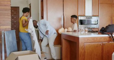 Aile mutfaktaki kutuları açıyor, takım çalışması ve gülücüklerle yeni bir ev düzenliyor. taşınma, taşınma, mutluluk, birliktelik