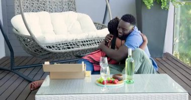 Afrika kökenli Amerikalı çift güvertede hediye kutusunu açıyor, kayıt belgelerini ve dava dosyalarını açıyorlar. Romantik, kutlama, açık hava, mutluluk, konfor, bağlantı, yaşam tarzı