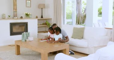 Afrika kökenli Amerikalı bir aile, kahve masası ve renkli kağıtlarla parlak bir evde proje üzerinde çalışıyor. Kardeşler, yaratıcılık, işbirliği, modern, aydınlık, samimi, oyuncu