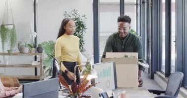 Yeni Siyahi meslektaşımızı karton kutu taşırken, eşyaları yerleştirirken, masada otururken karşılamak. İşbirliği, takım çalışması, modernlik, çalışma alanı, organizasyon, üretkenlik, profesyonel