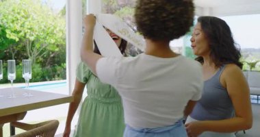 Müstakbel gelinin verandaya girmesi üzerine çeşitli bayan arkadaşlar gelin duşu için kuşak takıyorlar. Kutlama, dostluk, açık hava, zarafet, lüks, neşe, eğlence