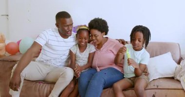 Ev partisini bej koltukta kutluyoruz renkli balonların ve dağınık konfetilerin tadını çıkarıyoruz. Kutlama, neşe, kahkaha, birliktelik, balonlar, konfeti, hayat dolu, rahat